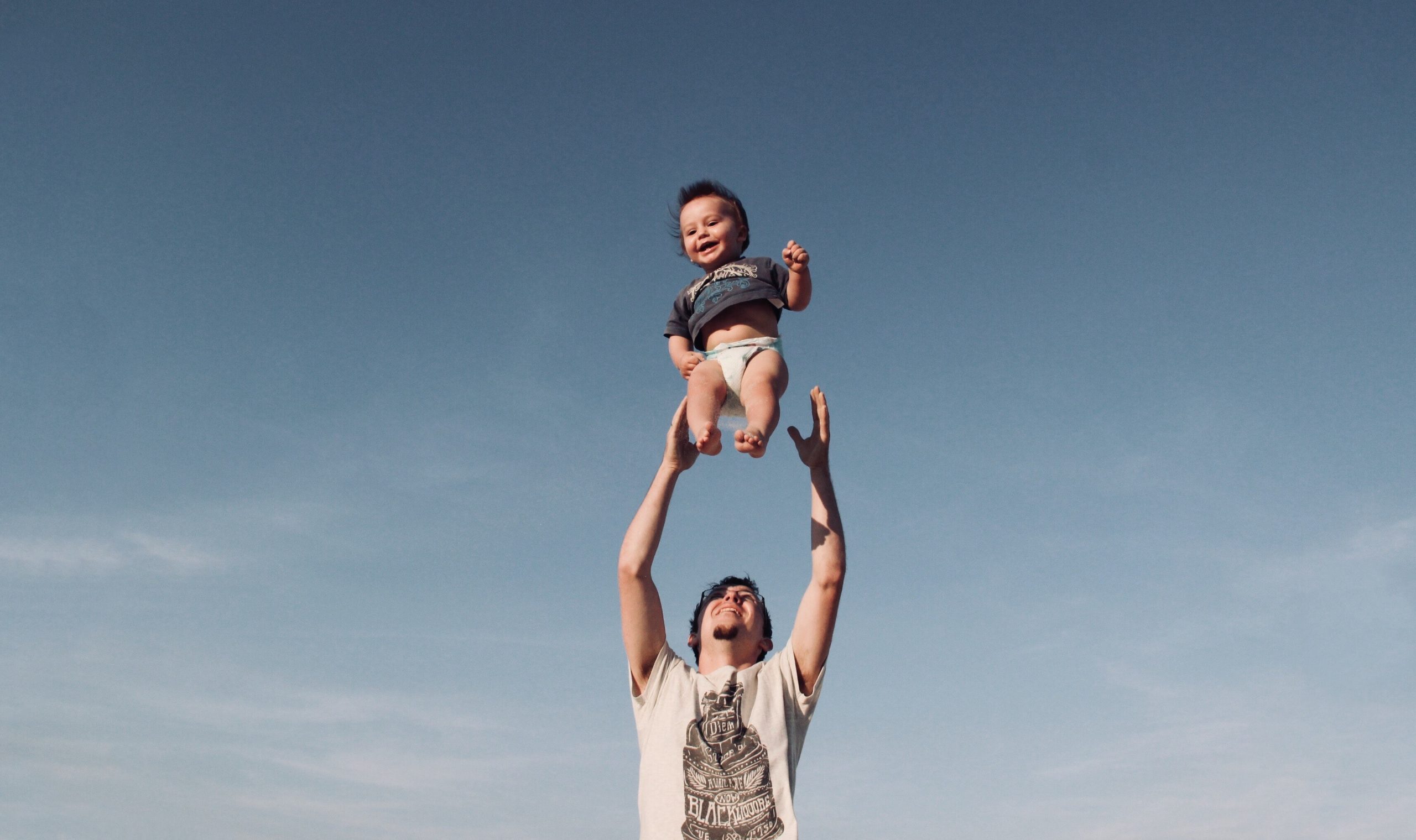 photo-of-man-in-raising-baby-under-blue-sky-1166990-scaled